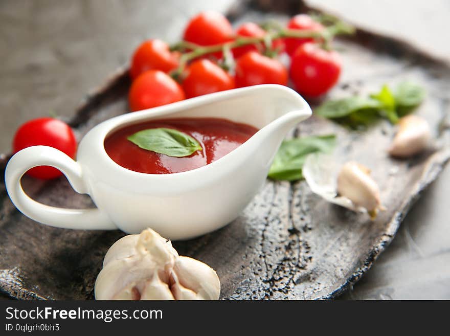 Gravy boat with red sauce and vegetables on plate