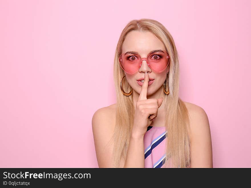 Beautiful young woman showing silence gesture on color background