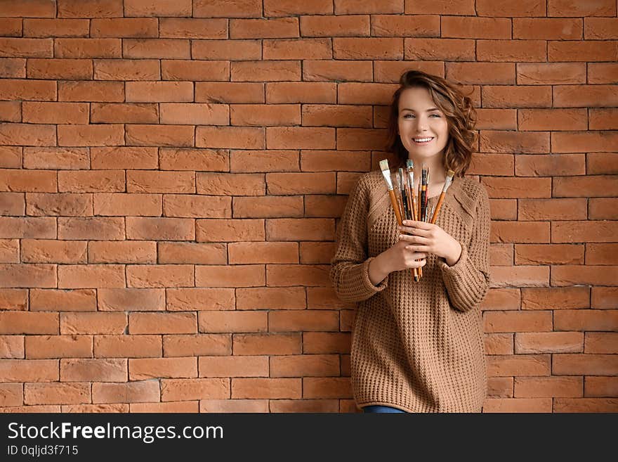 Female Artist With Brushes On Brick Wall Background