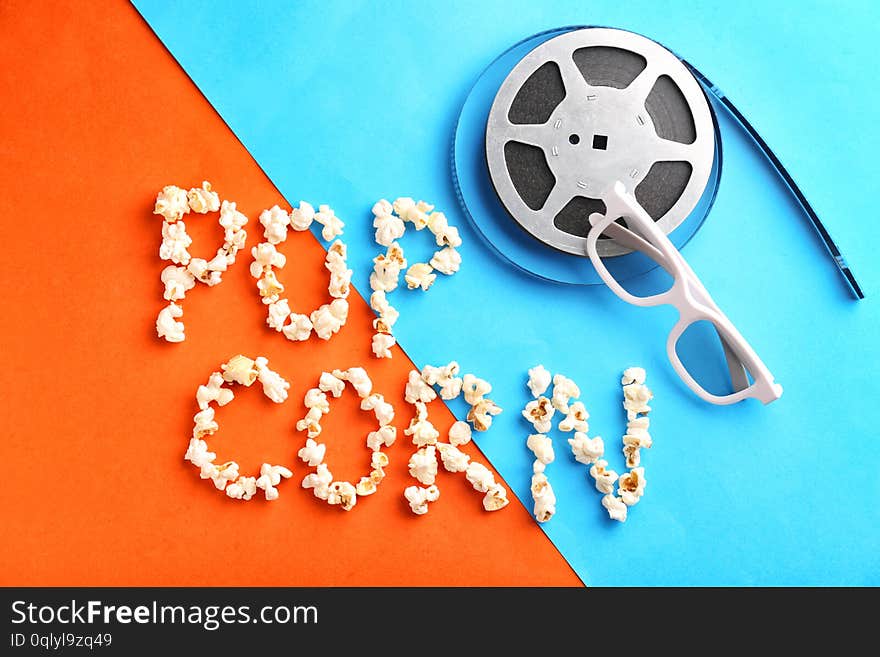 Composition with words POP CORN and film reel on color background