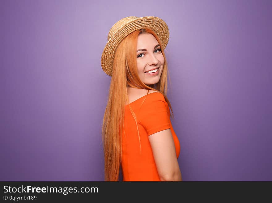 Beautiful young woman in hat on color background