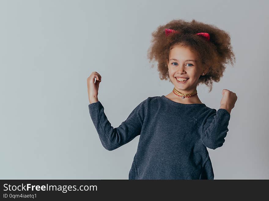 Headshot Portrait of happy girl  with curly hair  smiling looking at camera. gray background