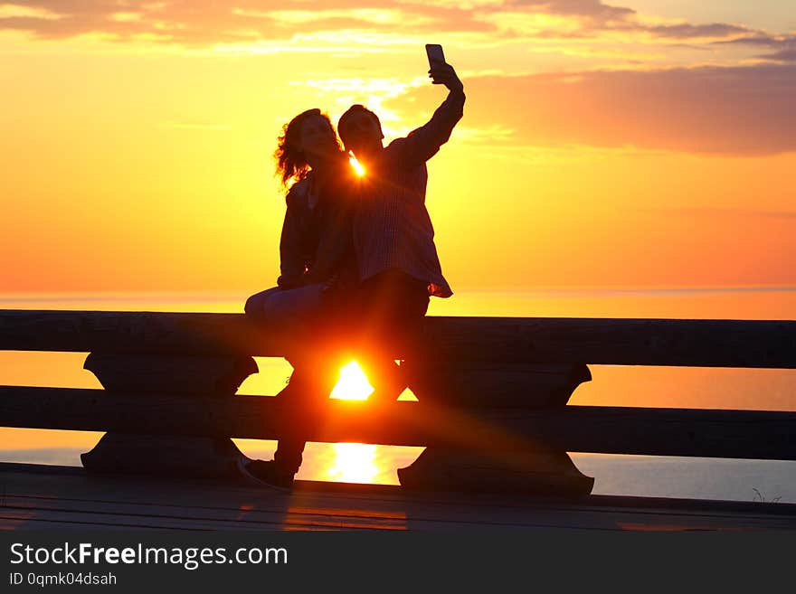 Silhouette young couple at sunset by the sea. Selfie