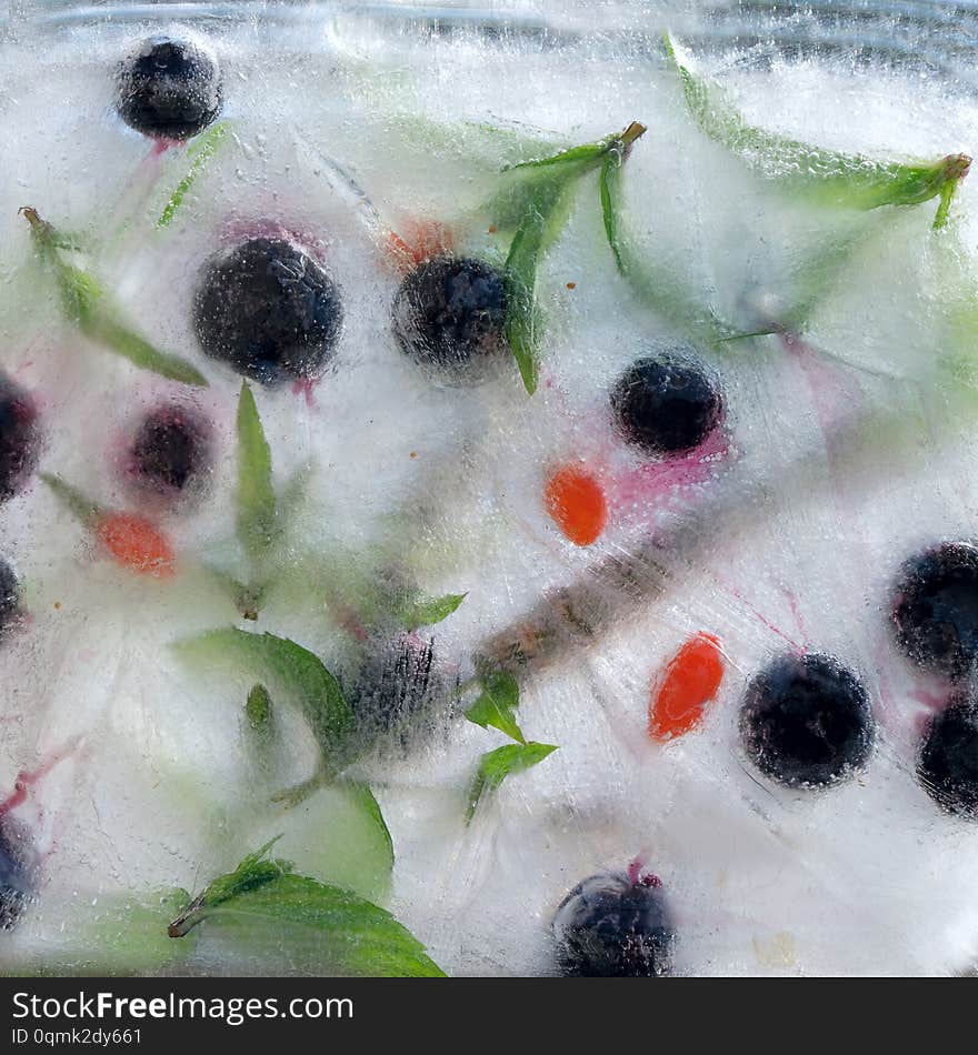 Background    green leaves of mint, berry of blueberry  Wolfberry, Goji berry,    in ice   cube with air bubbles. Background    green leaves of mint, berry of blueberry  Wolfberry, Goji berry,    in ice   cube with air bubbles