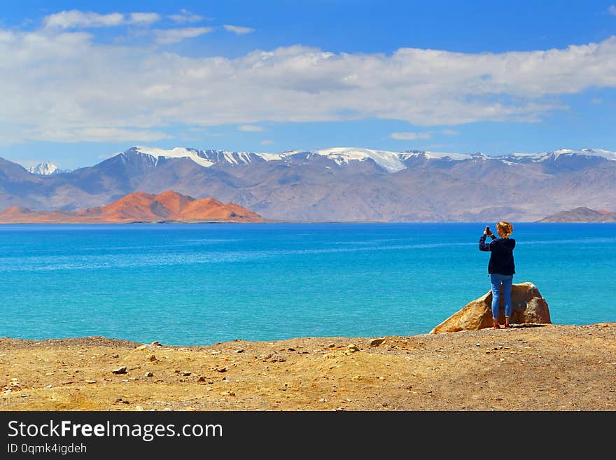 Tourist girl taking pictures of mountain landscape on phone while traveling