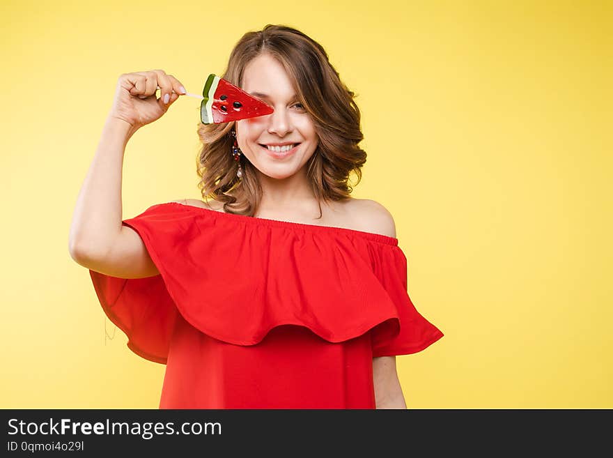 Close up portrait of attractive lovely girl in light dress handing lolipop isolated on yellow background. Close up portrait of attractive lovely girl in light dress handing lolipop isolated on yellow background