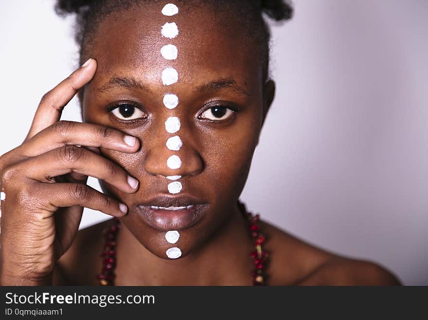 Painted face of young african girl with pattern from white dots close up