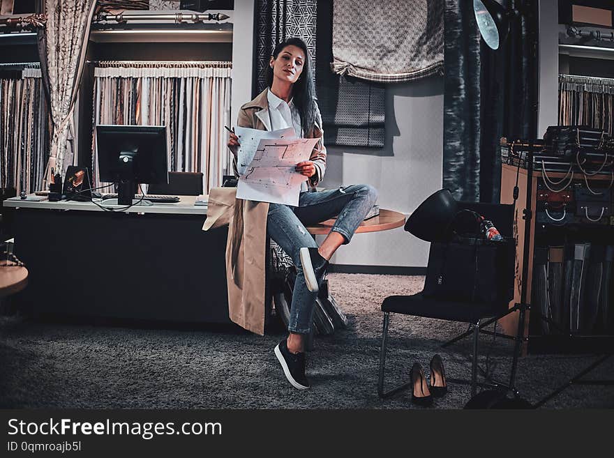 Cheerful designer is sitting on the table at her workshop