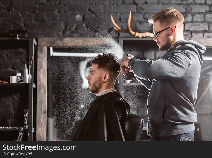 Hair cutting with metal scissors. Master cuts hair and beard of men in the barbershop, hairdresser makes hairstyle for a young man. Hair cutting with metal scissors. Master cuts hair and beard of men in the barbershop, hairdresser makes hairstyle for a young man.