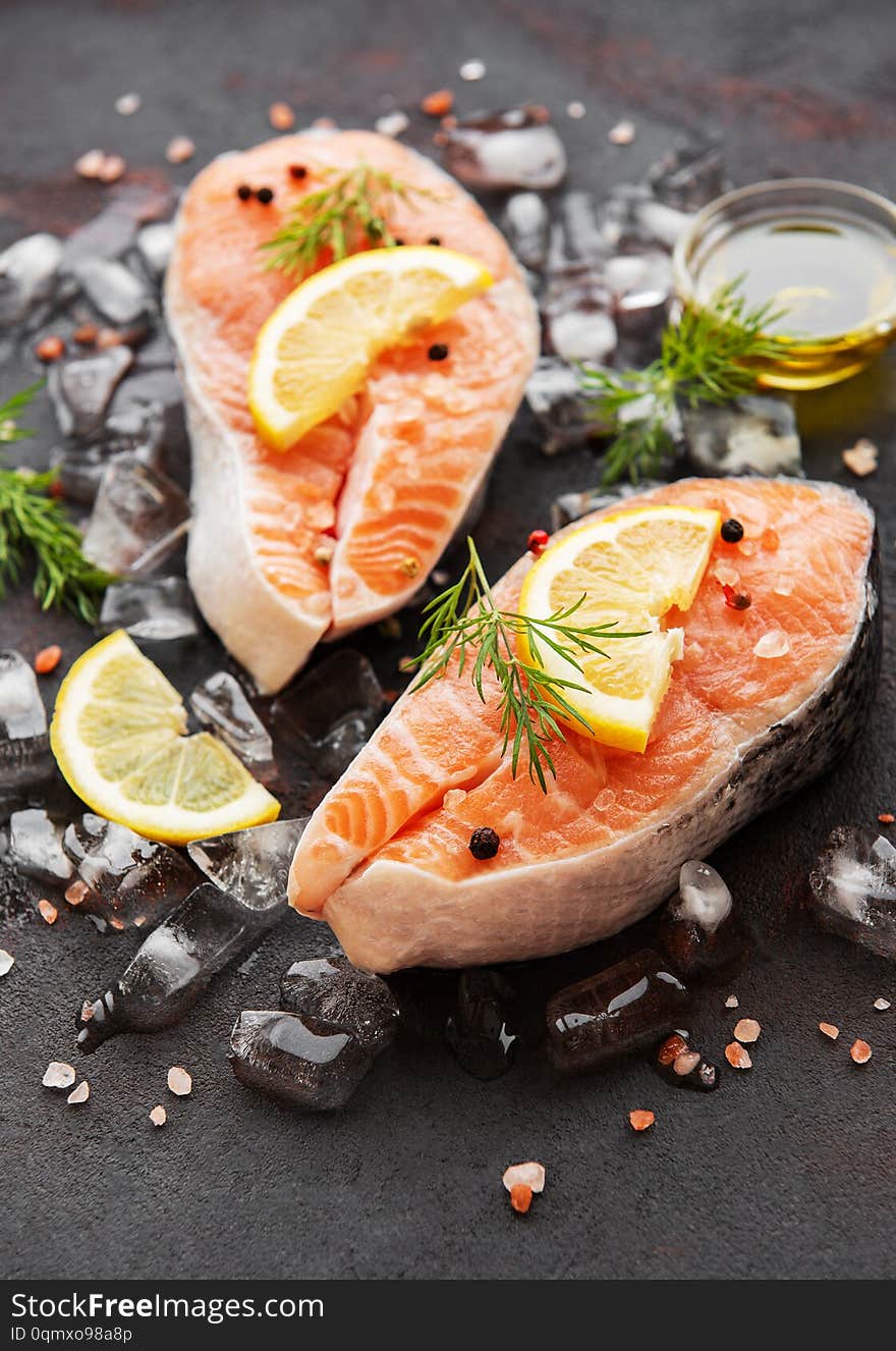 Raw salmon steaks and ingredients on a black slate board