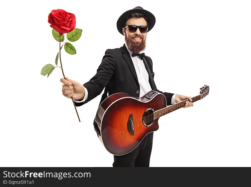 Young bearded man with an acoustic guitar holding a red rose isolated on white background