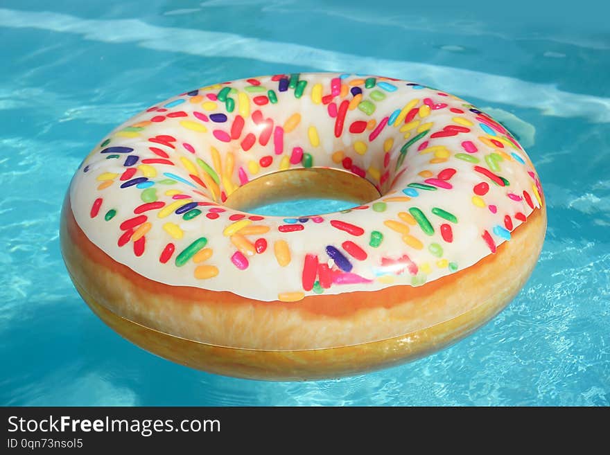 Bright inflatable doughnut ring floating in swimming pool on sunny day