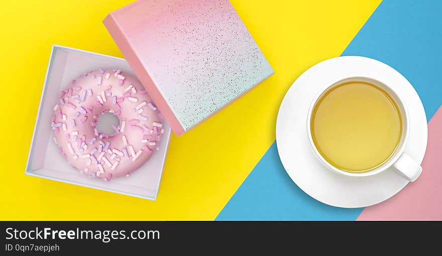 Gift box with donut and tea mug on pastel colorful background. Sweet food delivery concept. Top view. Flat lay.