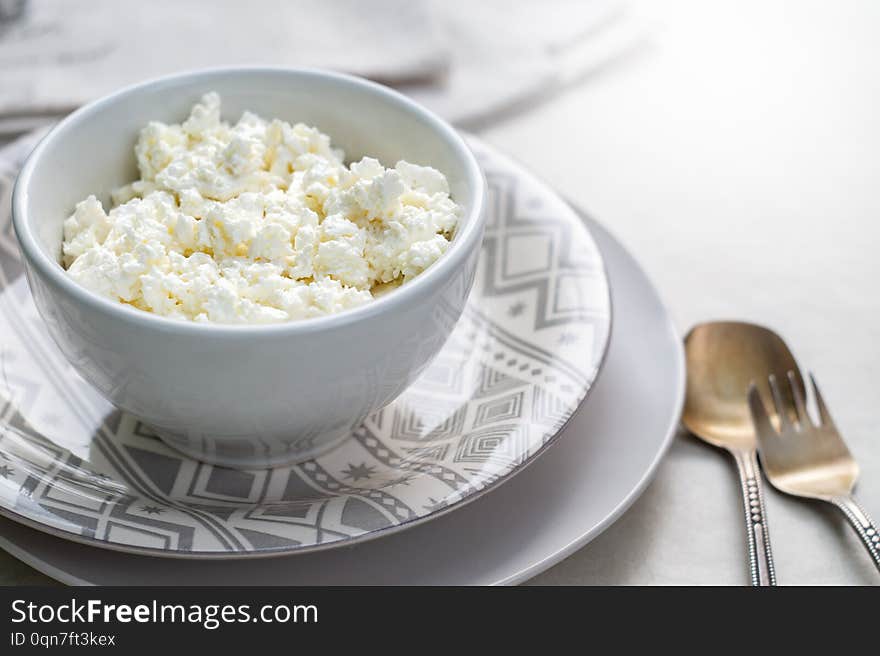 Cottage cheese on a white bowl on a gray background. The protein source