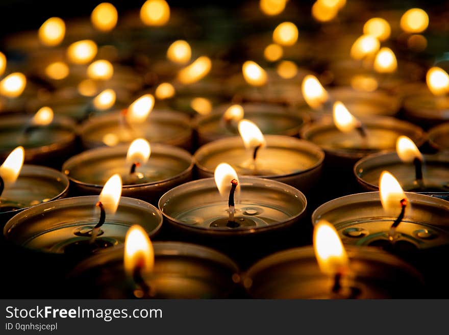 Many small burning candles on a wooden surface