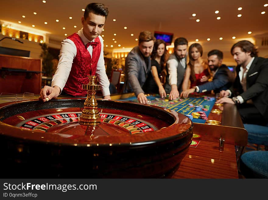 The Croupier Holds A Roulette Ball In A Casino In His Hand.