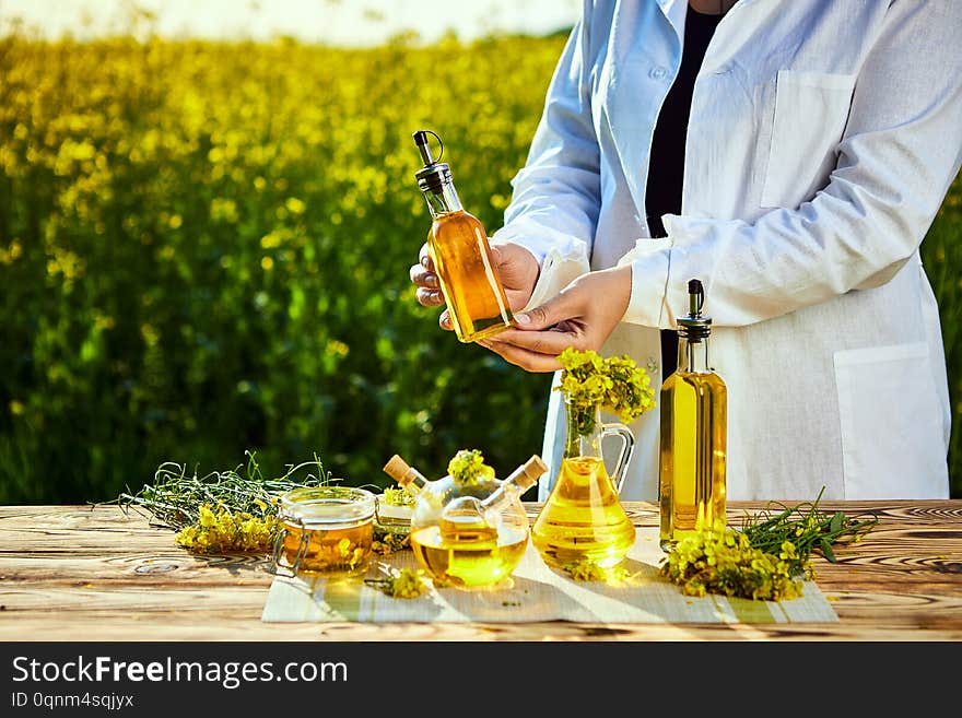 Rapeseed oil bottle in hand of an agronomist or biologist on background rape field