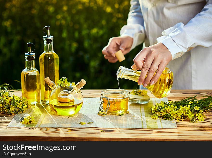 Rapeseed Oil Bottle In Hand Of An Agronomist Or Biologist On Background Rape Field