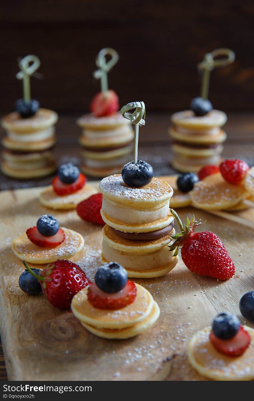 Fruit, berry and pancake very small canapes on wooden table. Sweet candybar for children. Fruit, berry and pancake very small canapes on wooden table. Sweet candybar for children