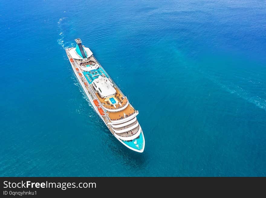 Cruise ship liner sails in the blue sea leaving a plume on the surface of the water seascape. Aerial view the concept of sea