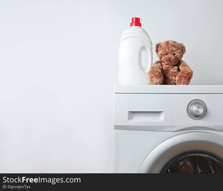 Bottle of liquid washing gel, teddy bear on a washing machine against a white background. Bottle of liquid washing gel, teddy bear on a washing machine against a white background