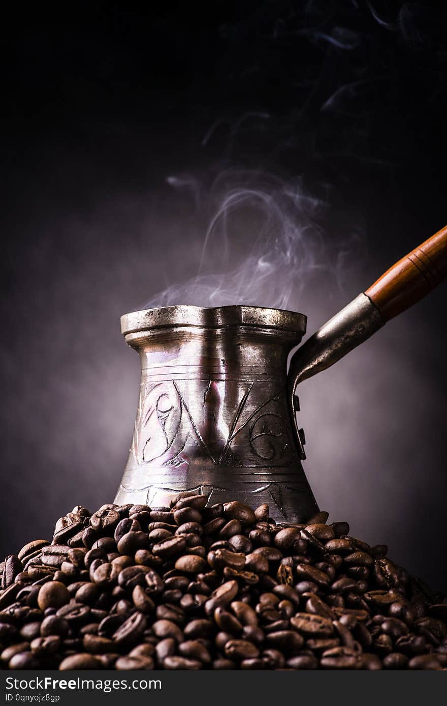 Still life. steaming Turkish coffee pot and pile of coffee beans with dark background. Still life. steaming Turkish coffee pot and pile of coffee beans with dark background