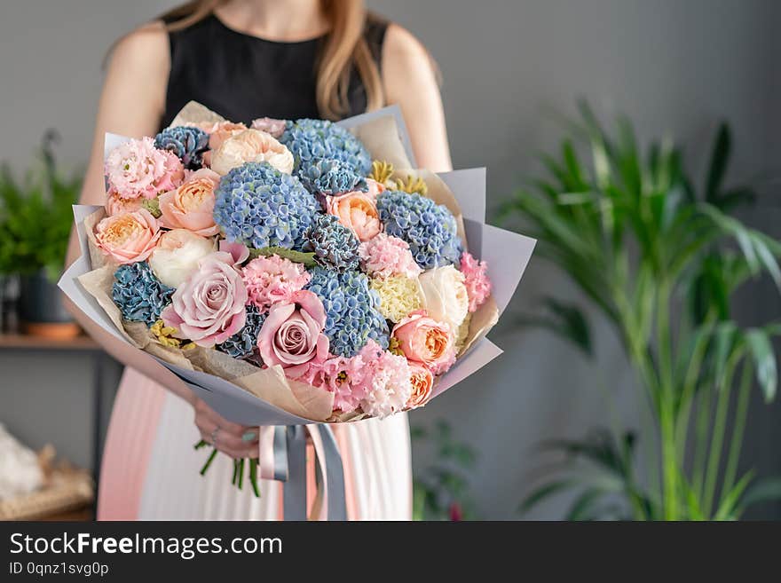 Beautiful bouquet of mixed flowers in woman hand. Floral shop concept . Handsome fresh bouquet. Flowers delivery. Blue