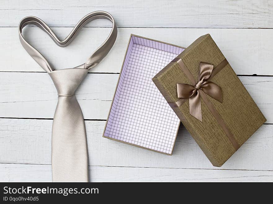 Gift box and necktie on wooden background.