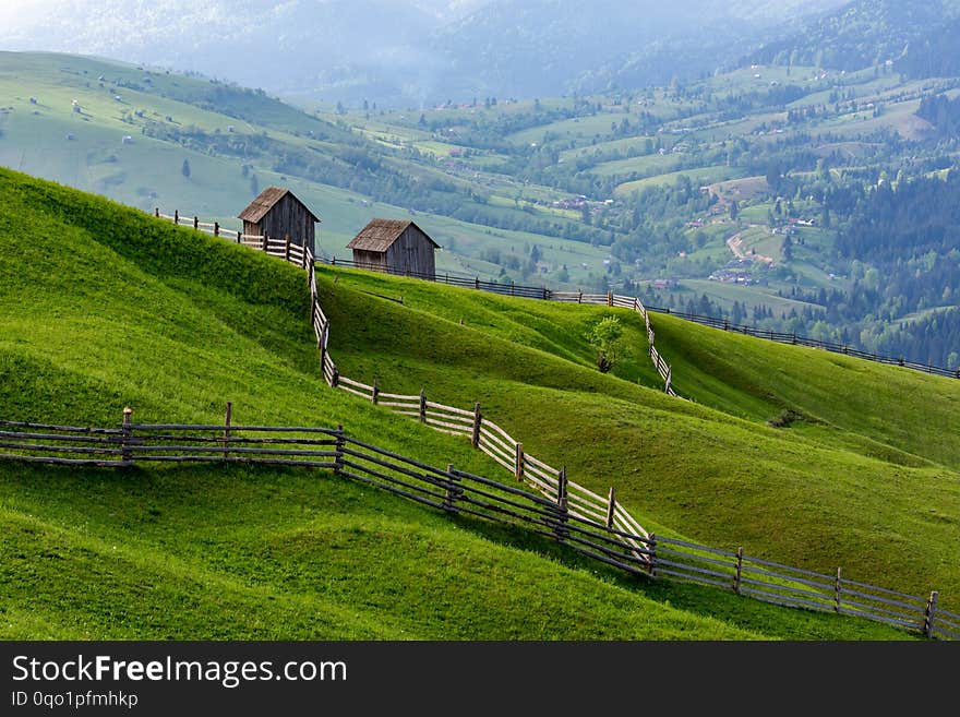 Landscape of a raw green meadow with leading lines to barns, Bucovina, Romania.