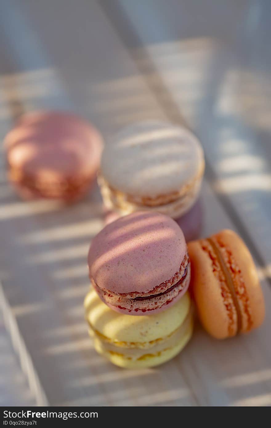 Sweet French pastries on a rustic table. Dessert macarons in the summer evening in the orchard. Sunlight. Natural blurred background. Shallow depth of field, bokeh and close-up. Copy space. Sweet French pastries on a rustic table. Dessert macarons in the summer evening in the orchard. Sunlight. Natural blurred background. Shallow depth of field, bokeh and close-up. Copy space.