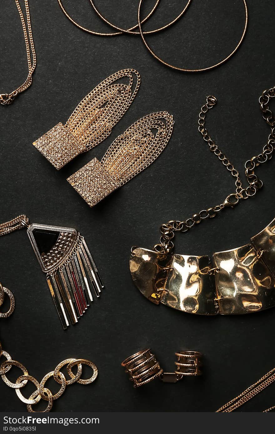 Set of gold jewelry on black background, flat lay