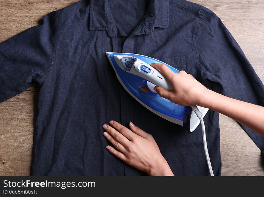 Woman ironing shirt on wooden background, top view