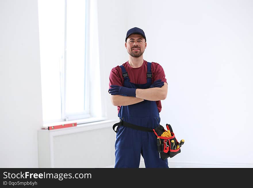 Portrait of professional construction worker with tool belt indoors