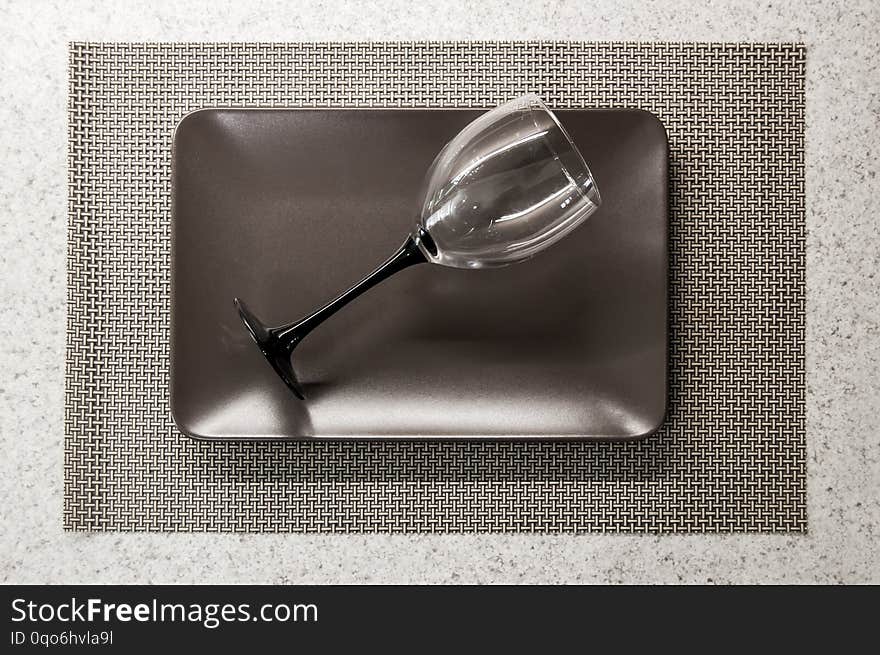 Lying empty wineglass on a brown plate on the tabletop