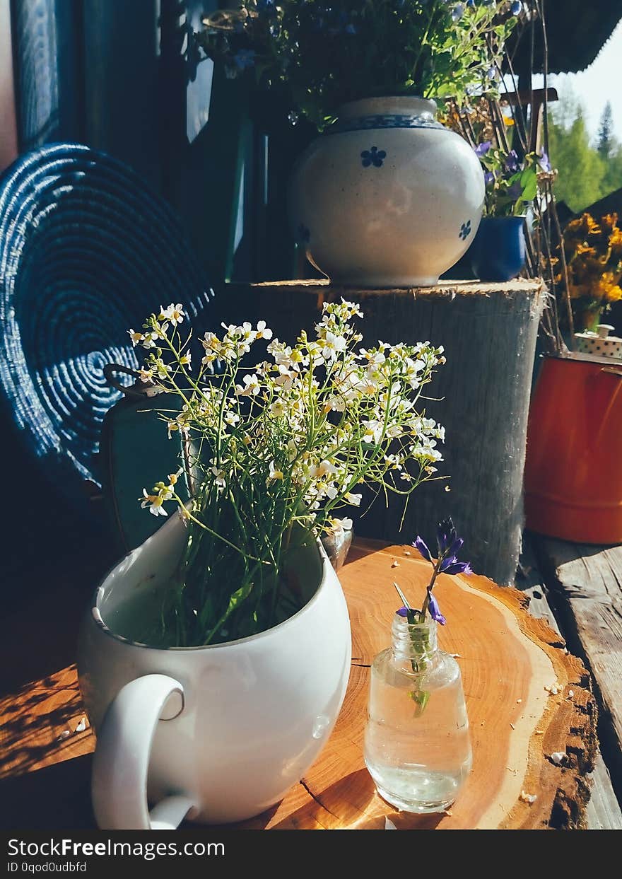 Bouquet of purple field flowers in white porcelain vase, blue round wicker plate and wooden background. Still life in rustic style, daylight. Countryside, Beauty, Nature, Lifestyle, Art concept. Bouquet of purple field flowers in white porcelain vase, blue round wicker plate and wooden background. Still life in rustic style, daylight. Countryside, Beauty, Nature, Lifestyle, Art concept