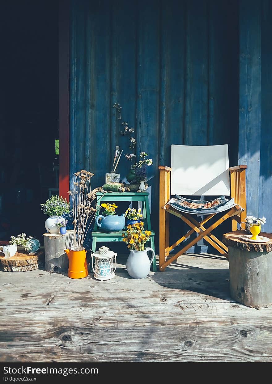 Wild flowers in vases, ceramic jars, pots, a chair, on blue wooden veranda background. Still life in rustic style, daylight. Beauty, Nature, Countryside lifestyle, weekend, vacation, art concept. Wild flowers in vases, ceramic jars, pots, a chair, on blue wooden veranda background. Still life in rustic style, daylight. Beauty, Nature, Countryside lifestyle, weekend, vacation, art concept