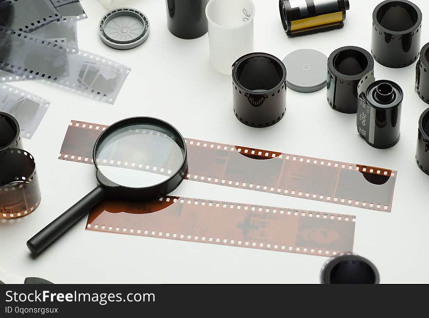 Multiple photographic films, scissors and magnifying glass on white background