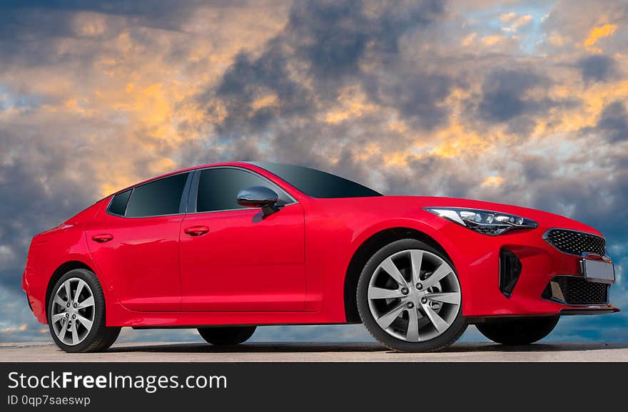 Red car on sunset sky background.