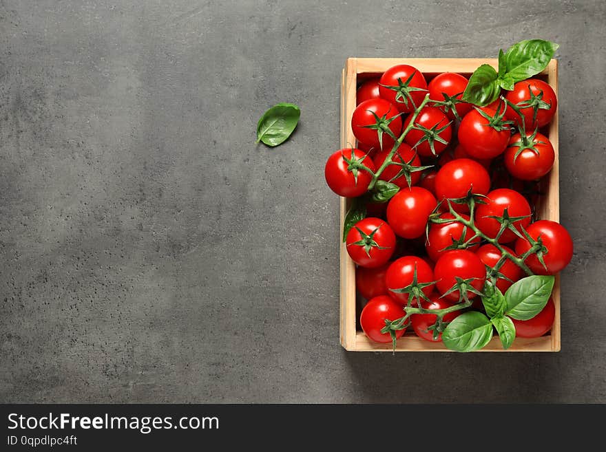 Crate with fresh cherry tomatoes on stone background, top view. Space for text