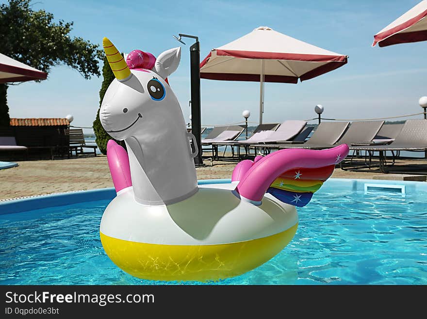 Funny inflatable unicorn ring floating in swimming pool on sunny day