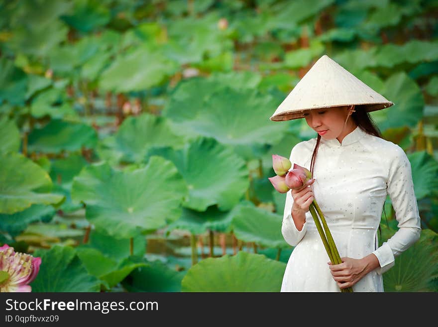 Vietnamese girl wearing a white dress holding a lotus flower. Vietnamese girl wearing a white dress holding a lotus flower