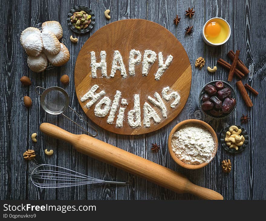 Happy holidays food background. Egg, flour and nuts are laid out on a dark wooden table.