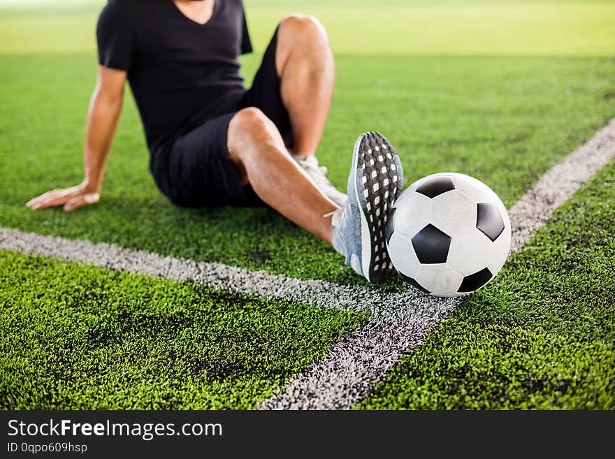 Soccer ball on green artificial turf with the player is stretch the muscles,warming up the body and foot before the competition or practicing. soccer academy