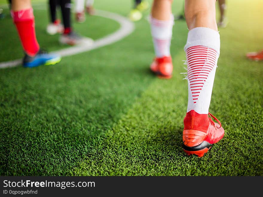 Soccer player Jogging on green artificial turf and stretching their feet. warming up the body and foot before the competition or practicing. soccer training. football or soccer academy