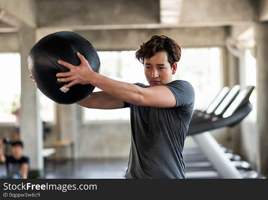 Man swing medicine ball in fitness gym. Athletic American man doing abdomen exercise at fitness gym. Man doing workout by swining hard medicine ball in sport club. Bodybuilding and healthy lifestyle concept, abdominal, adult, aesthetic, athlete, bicep, black, bodybuilder, boxer, city, copy, space, cross, guy, hands, handsome, happy, lifting, male, medical, motivation, muscle, muscular, people, physical, power, powerlifting, professional, strength, strong, training, weight, young