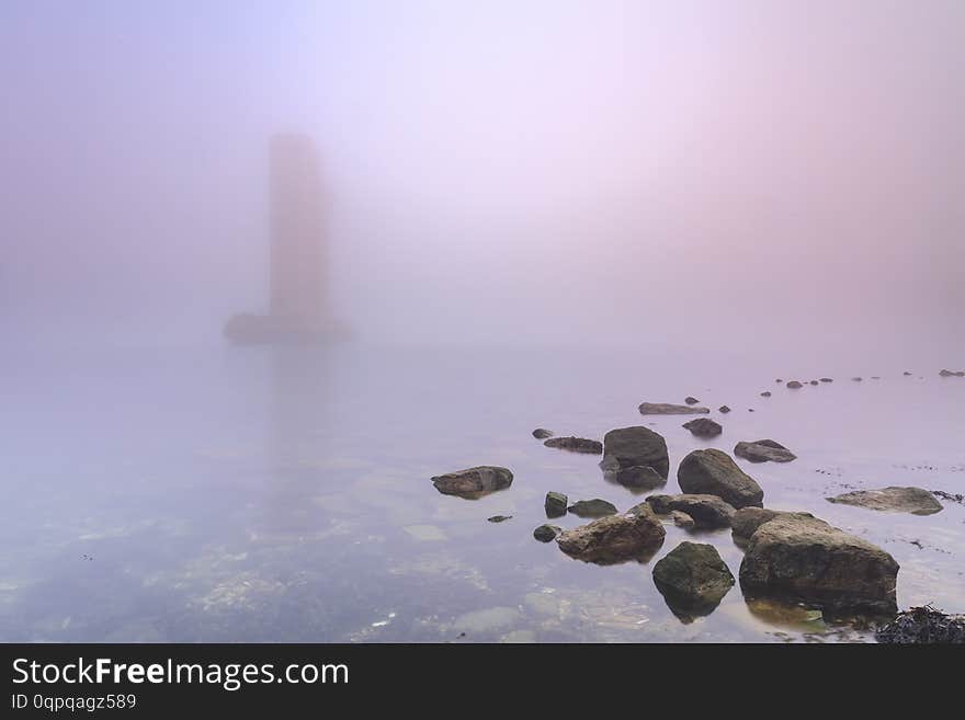 Pillar of a storm surge barrier in fog during sunset