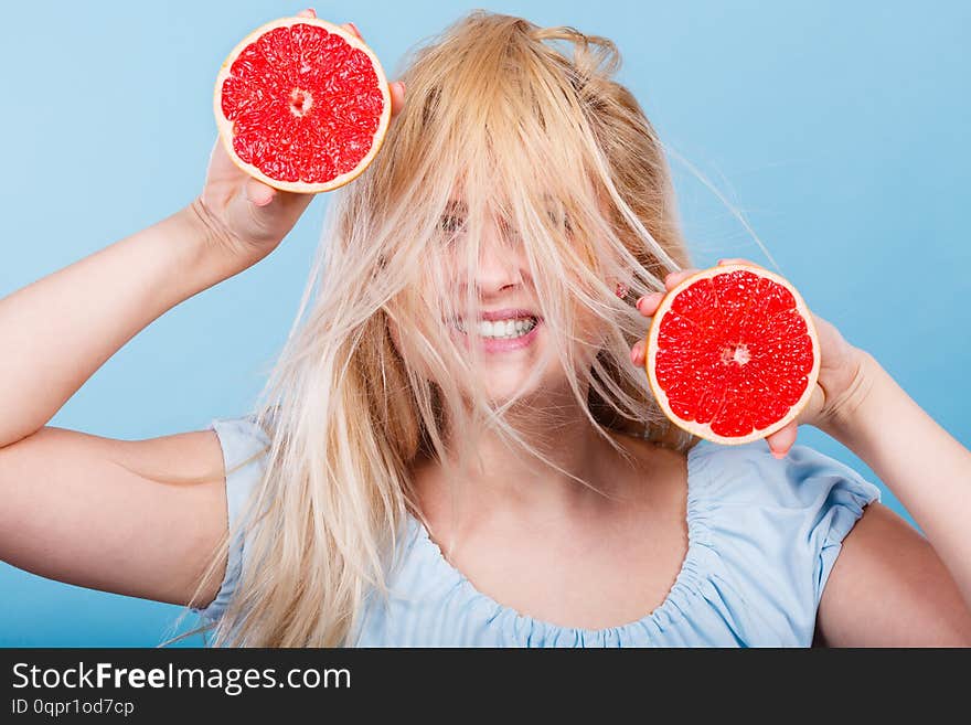 Healthy diet, refreshing food full of vitamins. Happy crazy woman holding sweet delicious citrus fruit, red grapefruit having windblown hair. Healthy diet, refreshing food full of vitamins. Happy crazy woman holding sweet delicious citrus fruit, red grapefruit having windblown hair