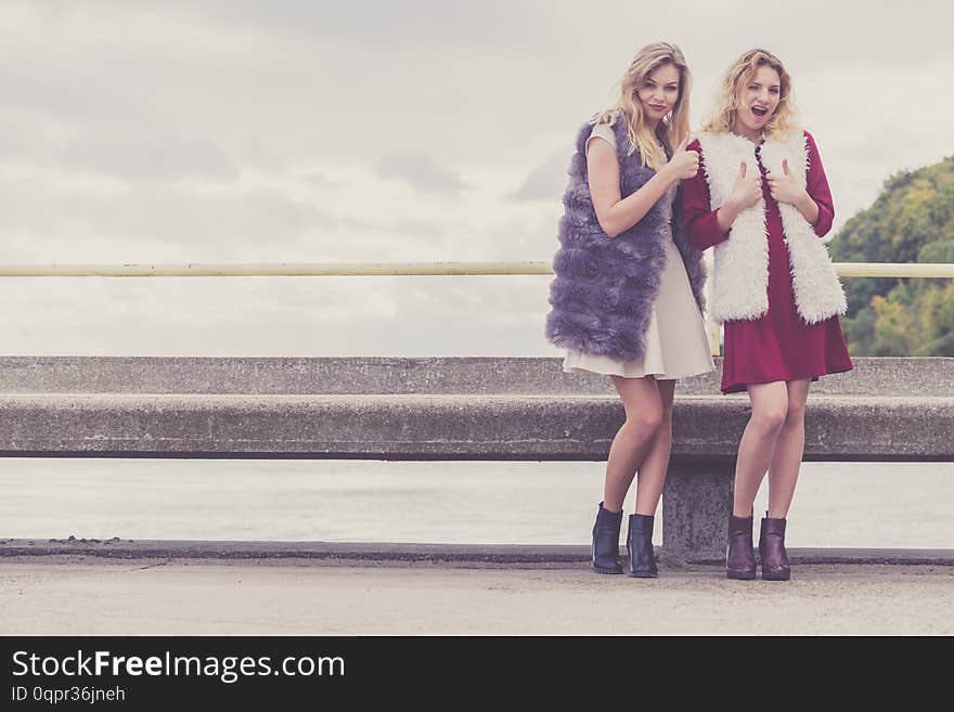 Two fashionable women wearing stylish outfits during warm autumnal weather spending their free time outdoor. Two fashionable women wearing stylish outfits during warm autumnal weather spending their free time outdoor