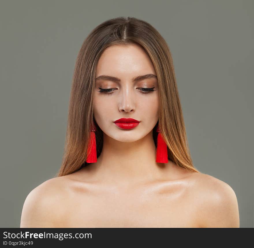 Beautiful fashion model woman with red jewelry earrings portrait.