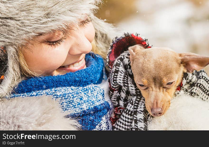 Young woman wrapped her best friend little dog in warm blanket scarf to warm him in cold snowy winter day. Animal protection save. Adoption concept. Young woman wrapped her best friend little dog in warm blanket scarf to warm him in cold snowy winter day. Animal protection save. Adoption concept